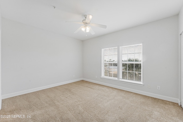 carpeted spare room with ceiling fan and baseboards