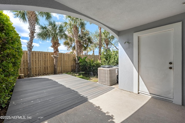 wooden terrace featuring a patio, central AC unit, and fence