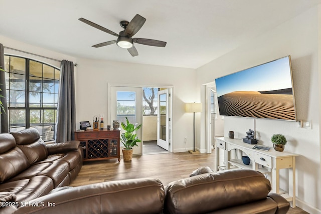 living area with wood finished floors, a ceiling fan, and baseboards