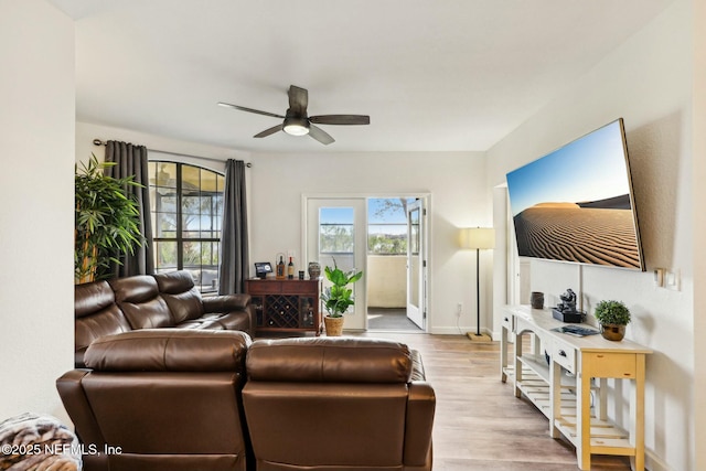 living room with ceiling fan, baseboards, and wood finished floors