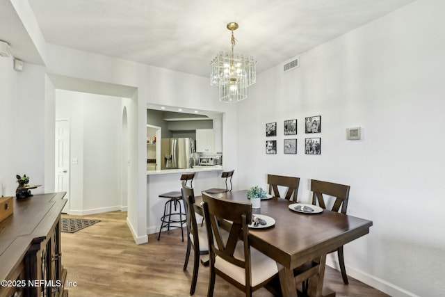 dining area featuring an inviting chandelier, wood finished floors, visible vents, and baseboards