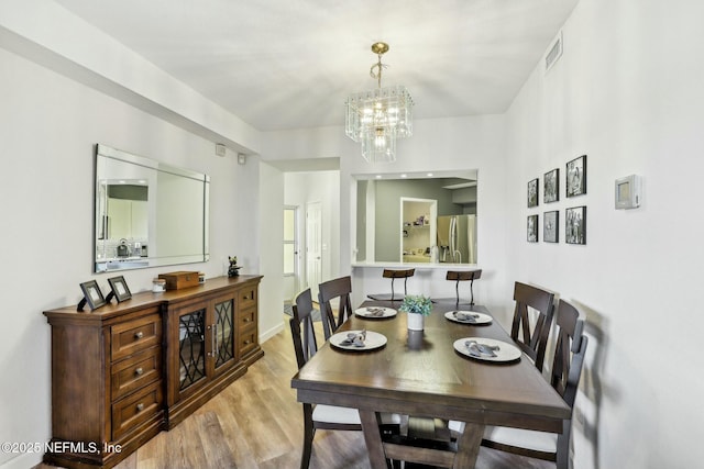 dining room featuring light wood finished floors, visible vents, and a chandelier