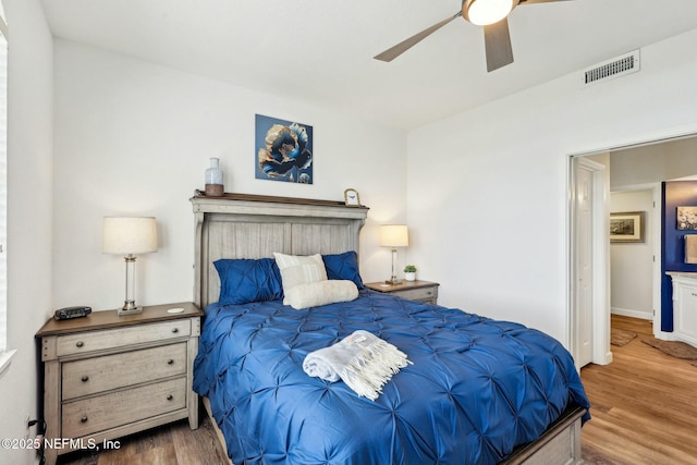 bedroom with baseboards, ceiling fan, visible vents, and wood finished floors