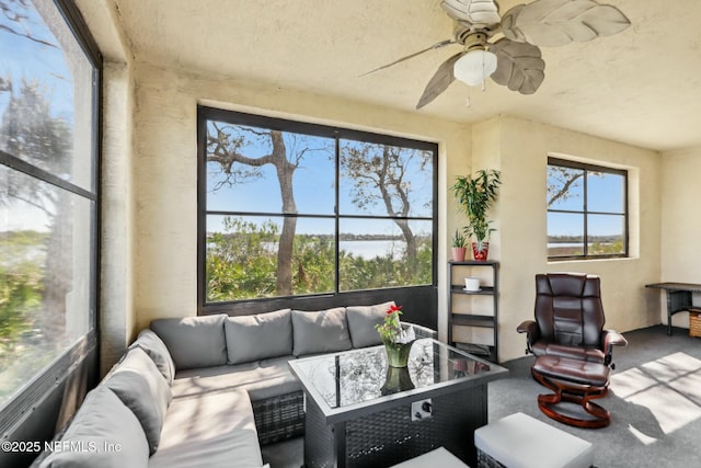 sunroom / solarium featuring a water view and a ceiling fan