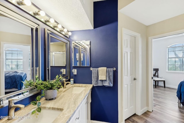 bathroom with a sink, baseboards, connected bathroom, and wood finished floors