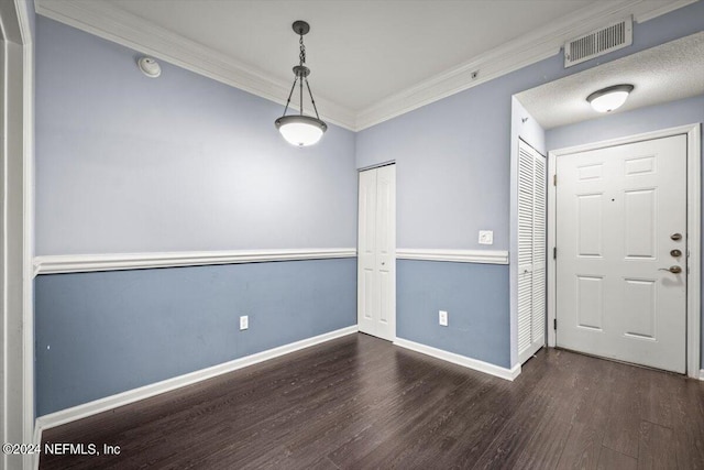 empty room featuring ornamental molding, visible vents, dark wood finished floors, and baseboards