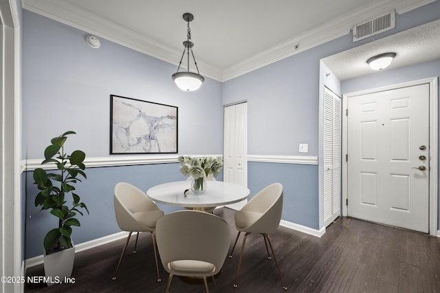 dining room featuring dark wood-style floors, visible vents, crown molding, and baseboards