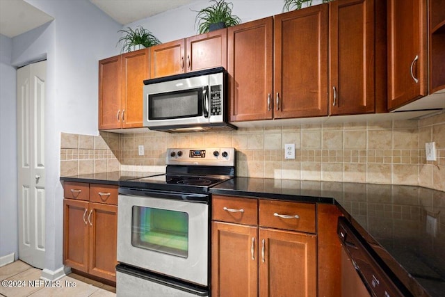 kitchen featuring brown cabinets, stainless steel appliances, dark countertops, backsplash, and light tile patterned flooring