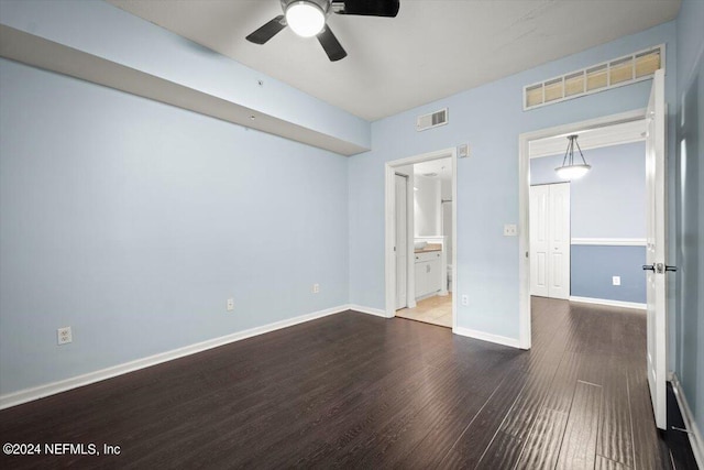 unfurnished bedroom with baseboards, visible vents, connected bathroom, ceiling fan, and wood finished floors