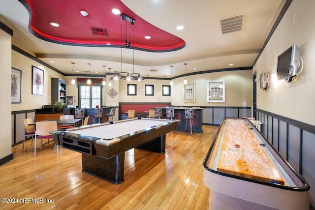 recreation room with light wood-style floors, visible vents, a tray ceiling, and crown molding