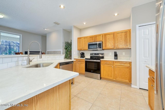kitchen featuring appliances with stainless steel finishes, light tile patterned flooring, light countertops, a sink, and recessed lighting