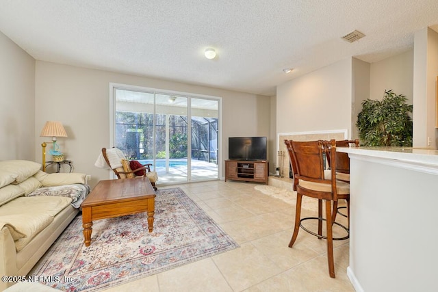 living area featuring light tile patterned floors, visible vents, and a textured ceiling