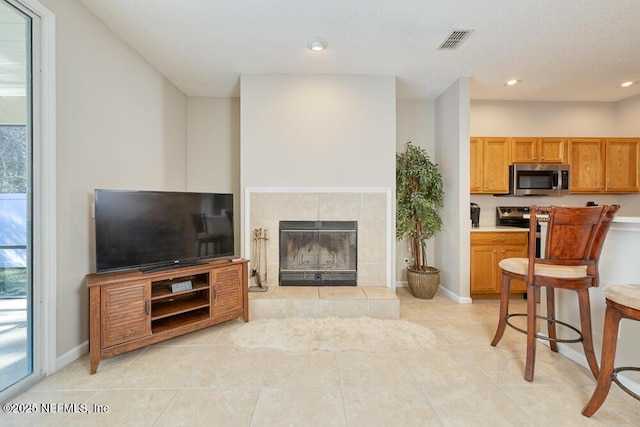 living room featuring recessed lighting, visible vents, baseboards, and a tile fireplace