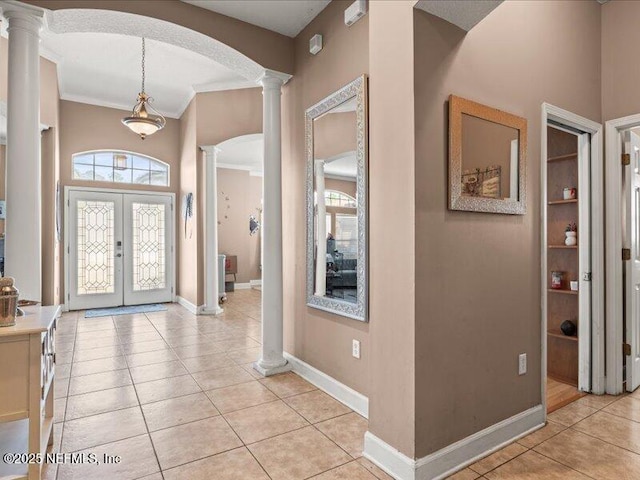 foyer with light tile patterned floors, french doors, decorative columns, and crown molding