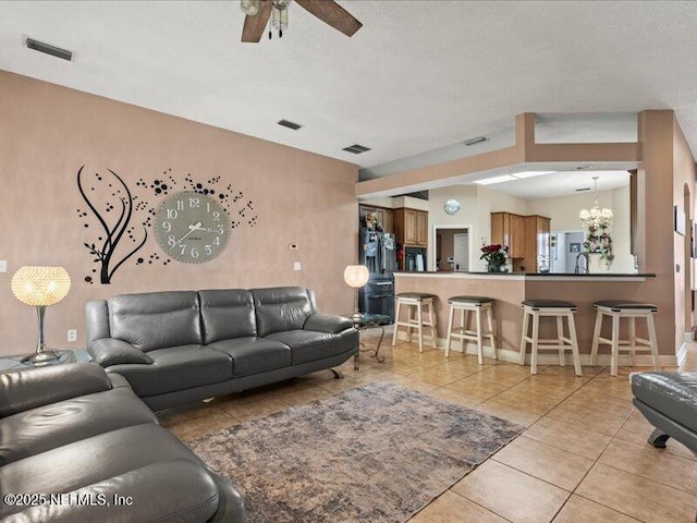 living area with ceiling fan with notable chandelier, light tile patterned flooring, and visible vents