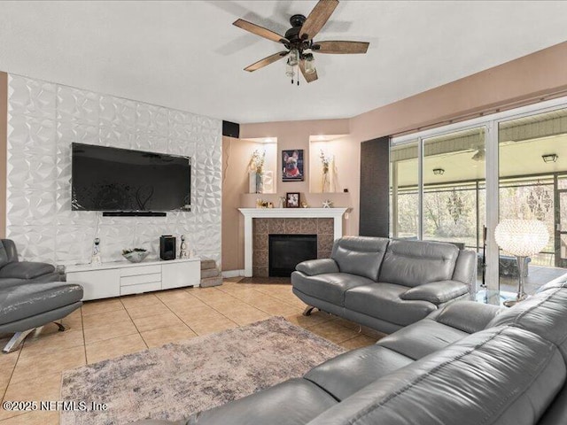 living area with baseboards, light tile patterned flooring, ceiling fan, and a tiled fireplace