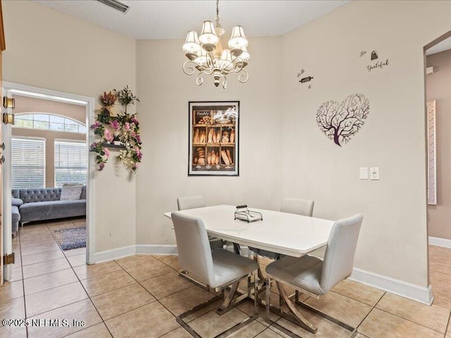 dining area featuring light tile patterned floors, a notable chandelier, and baseboards