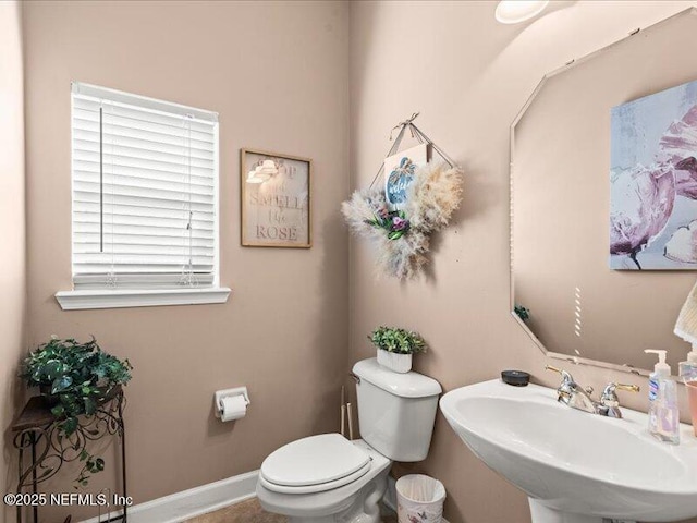 bathroom with a sink, toilet, and baseboards