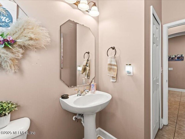 bathroom featuring baseboards, a closet, toilet, and tile patterned floors