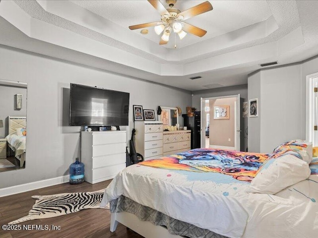 bedroom featuring a raised ceiling, baseboards, visible vents, and dark wood-style flooring