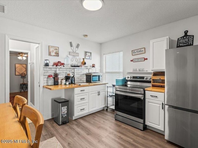 kitchen featuring wooden counters, appliances with stainless steel finishes, and white cabinets