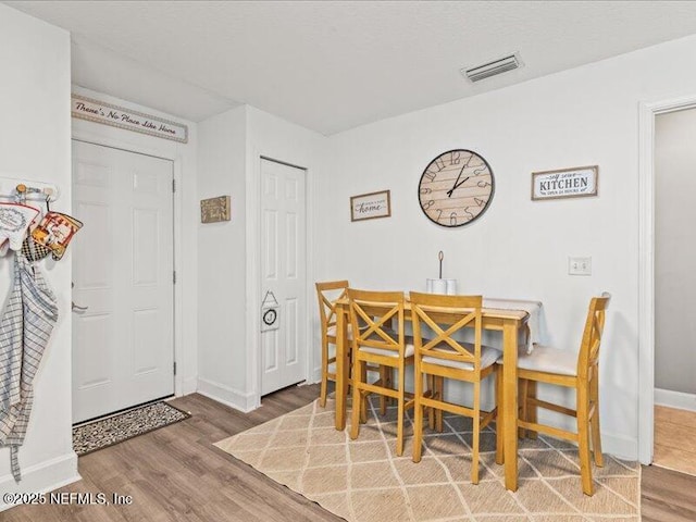 dining room with visible vents, baseboards, and wood finished floors