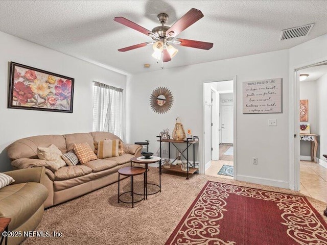 living area featuring a textured ceiling, ceiling fan, light tile patterned floors, and visible vents