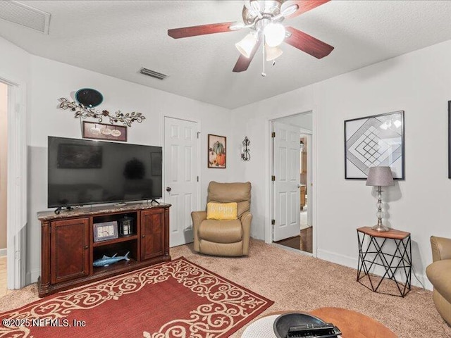 carpeted living area with ceiling fan, visible vents, and a textured ceiling