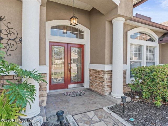 entrance to property with stone siding, french doors, and stucco siding