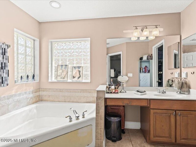 bathroom with a garden tub, vanity, and tile patterned floors