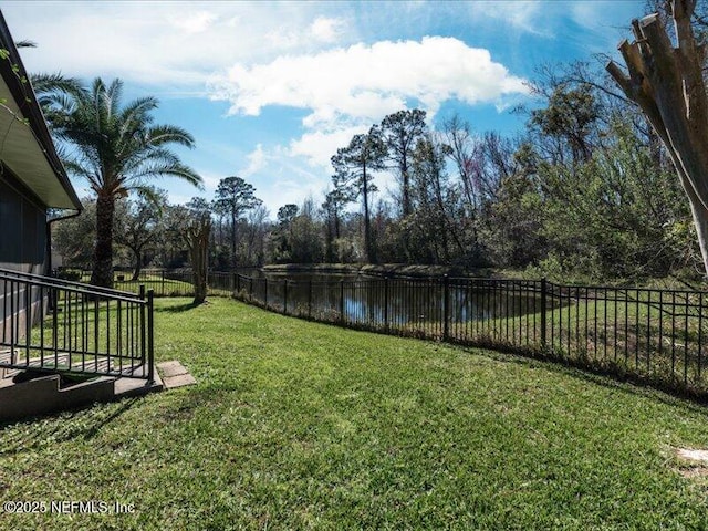 view of yard with a water view and a fenced backyard