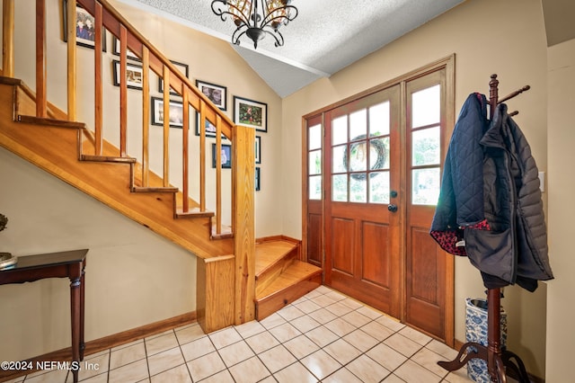 foyer entrance with light tile patterned floors, lofted ceiling, stairway, an inviting chandelier, and a textured ceiling