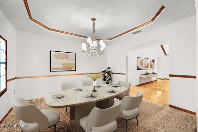 dining room with a textured ceiling, a raised ceiling, visible vents, and an inviting chandelier