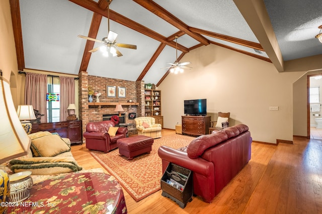 living room featuring light wood finished floors, a brick fireplace, a textured ceiling, beamed ceiling, and baseboards