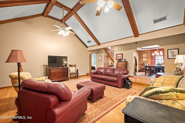 living area with ceiling fan with notable chandelier, arched walkways, wood finished floors, and stairs