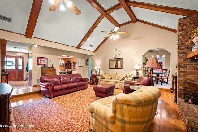 living room featuring arched walkways, a textured ceiling, ceiling fan with notable chandelier, visible vents, and light wood-type flooring