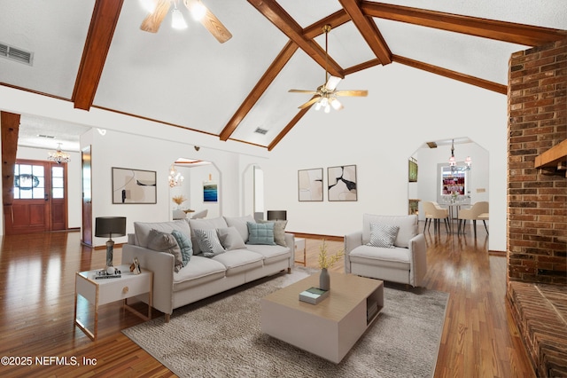 living area with dark wood-style floors, visible vents, arched walkways, and ceiling fan with notable chandelier