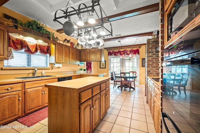 kitchen featuring a textured ceiling, a sink, light countertops, a center island, and brown cabinetry