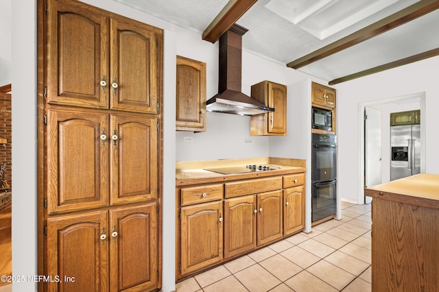 kitchen featuring wall chimney exhaust hood, light tile patterned floors, light countertops, a textured ceiling, and black appliances