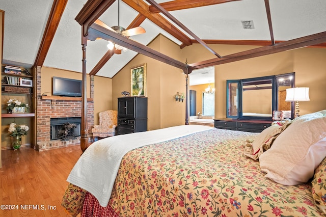 bedroom featuring visible vents, lofted ceiling with beams, a brick fireplace, a textured ceiling, and light wood-type flooring