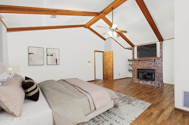 bedroom featuring lofted ceiling with beams, a fireplace, visible vents, and wood finished floors