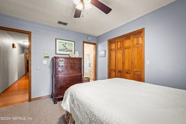 bedroom with a textured ceiling, visible vents, a ceiling fan, a closet, and ensuite bath