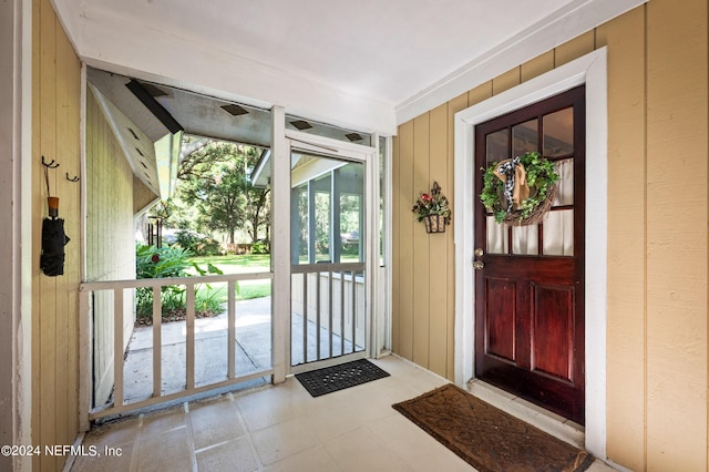 doorway to outside with wooden walls