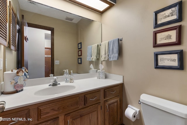 bathroom with visible vents, vanity, and toilet