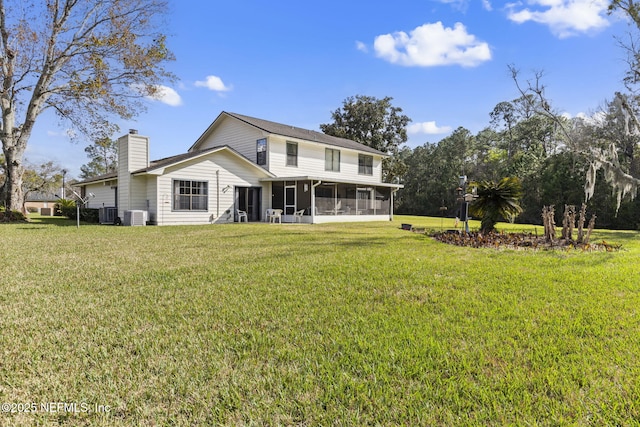 rear view of property featuring a sunroom, a lawn, and a chimney