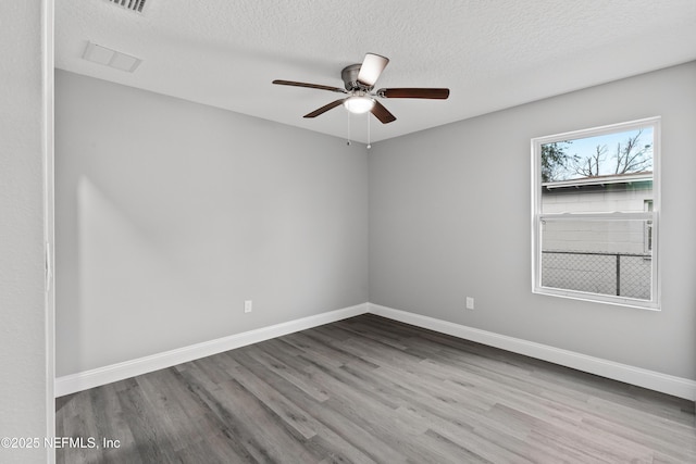 empty room featuring light wood-style floors, ceiling fan, a textured ceiling, and baseboards