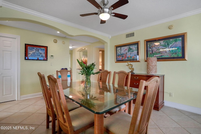 dining room with arched walkways, light tile patterned floors, visible vents, and crown molding