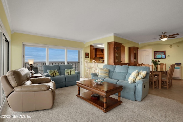 tiled living area with arched walkways, crown molding, and ceiling fan