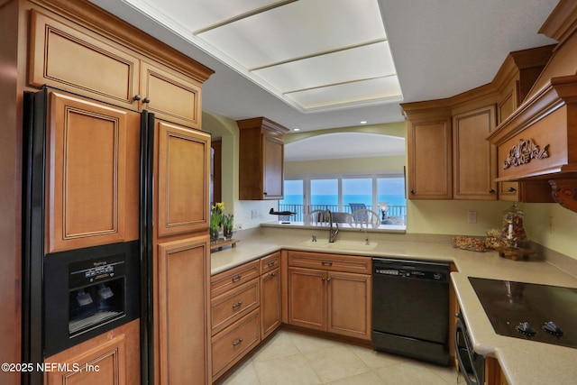 kitchen with black appliances, light countertops, a sink, and brown cabinetry