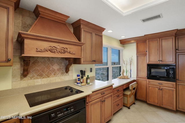 kitchen featuring premium range hood, visible vents, light countertops, brown cabinets, and black appliances